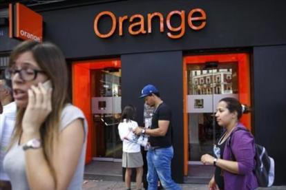 Personas pasan por delante de una tienda de Orange en Madrid.
