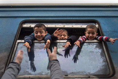 Niños saludan desde un autobús con destino a Serbia. G. LICOVSKI