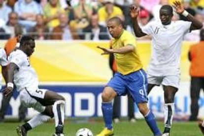 El brasileño Ronaldo lucha por el balón con los jugadores de Ghana Sulley Muntari y John Mensah