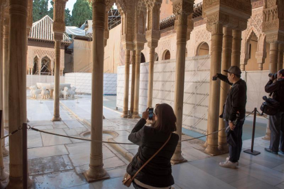 Unos turistas fotografían el Patio de los Leones de la Alhambra de Granada.