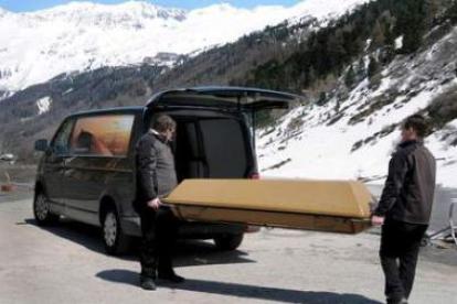 Dos operarios trasladan el ataúd de uno de los fallecidos en los Alpes