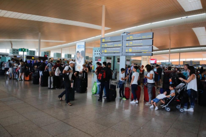 Colas de pasajeros esperando para facturar en los mostradores de Vueling en la T-1 del aeropuerto de El Prat.