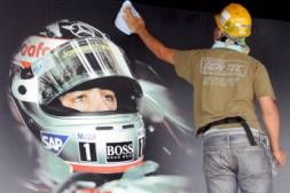 Un obrero limpia un cartel con la fotografía del piloto español de Fórmula Uno, Fernando Alonso