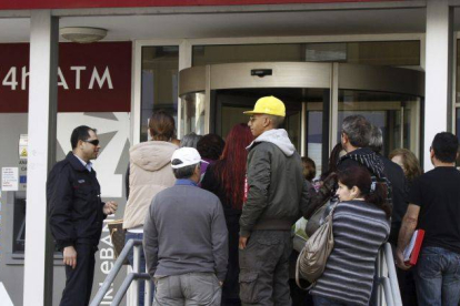 Varias personas hacen cola a las puertas de una sucursal del Banco Laiki en Nicosia.
