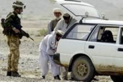 Un miembro de la marina británica inspecciona el vehículo de un afgano, al sureste del país