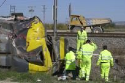 Unos operarios retirar los restos del camión que chocó contra el tren de Zaragoza