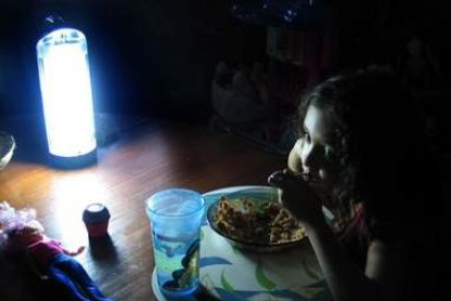 Una niña come alumbrada por una lámpara.