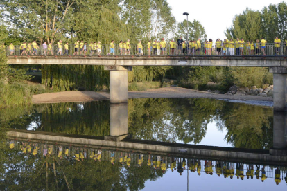 Los participantes en la marcha atraviesan el puente peatonal del río Cea. ACACIO