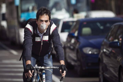 un ciclista con una mascarilla circulando hoy por las calles de Madrid