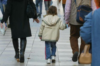 Unos padres pasean con su hijo, cogidos de la mano.