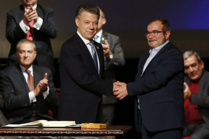 Santos (izquierda) y Rodrigo Londoño, alias 'Timochenko', se dan la mano tras firmar el nuevo acuerdo, en Bogotá, este jueves.