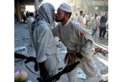Un fiel chií besa a un miliciano de Al Sáder en los alrededores de la mezquita de Nayaf