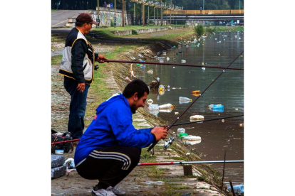 Ds hombres pescan en el río Vardar, cubierto de botellas y basura. GEORGI LICOVSKI