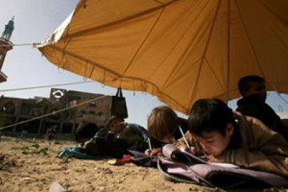 Niños palestinos asisten a clase en una tienda instalada entre los restos de su escuela destruída.