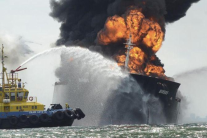 Una embarcación intenta sofocar las llamas del buque cisterna.