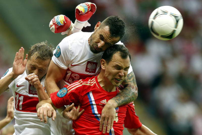 Los jugadores de Polonia Murawski y Wasilewski buscan el balón ante Ignashevich, de Rusia.