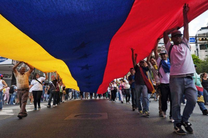 Un grupo de ciudadanos porta una bandera venezolana gigante, este domingo en Caracas, durante la marcha contra el Gobierno.