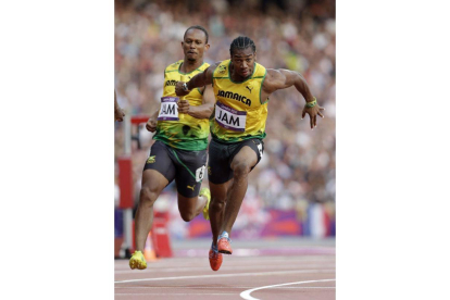 El jamaicano Michael Frater (izquierda) entrega el relevo a su compañero Yohan Blake (derecha) durante la semifinal de relevos 4x100. Foto: AP