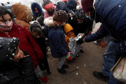 Imagen de una fundación repartiendo juguetes bajo la nieve a los niños de la Cañada Real. MARISCAL