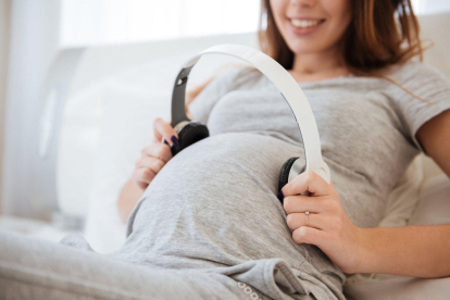 Una embarazada se pone unos auriculares en la tripa para estimular musicalmente al bebé.