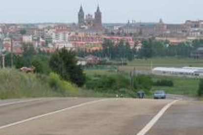 Un vehículo circula por la carretera Astorga-Nogarejas con la capital maragata al fondo de la imagen