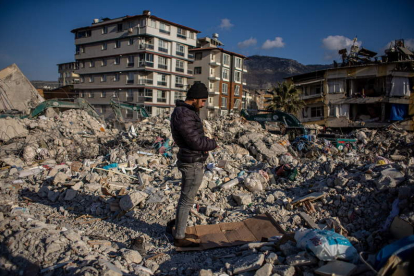 Un hombre reza en Hatay sobre los escombros de un edificio derrumbado por el terremoto. MARTIN DIVISEK