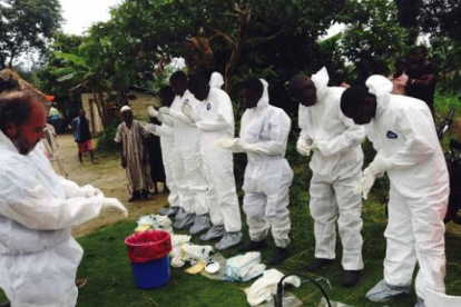 Voluntarios preparándose para ponerse los monos de aislamiento para tratar con enfermos de ébola, en Sierra Leona.