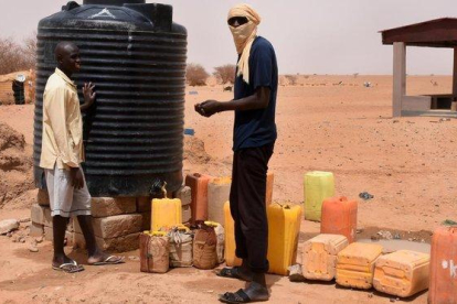 Dos refugiados recogen agua en un tanque en un campo de Níger.