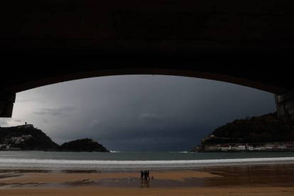 Unas personas caminan con sus perros por la playa de la Concha de San Sebastián. JUAN HERRERO