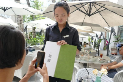 Una joven paga su consumición en un terraza de Shanghái con el teléfono móvil.