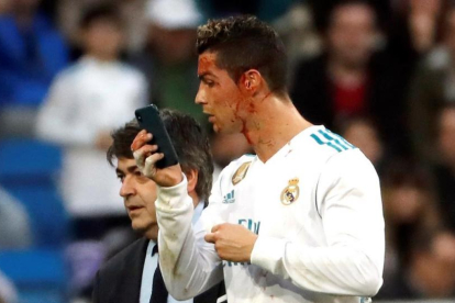Cristiano abandona el césped del Bernabéu mirándose la brecha en la ceja en el móvil del médico.