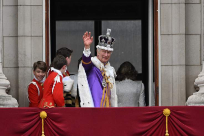 El rey Carlos III saluda desde el palco de Buckinham Palace tras ser coronado. NEIL HALL