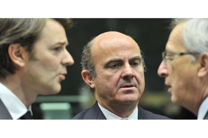 El ministro Guindos (centro) charlando con el presidente del Eurogrupo, Jean-Claude Juncker (derecha), y el ministro de Finanzas francés, François Baroin (a la izquierda).