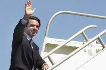 Aznar saluda mientras sube la escalerilla de un avión