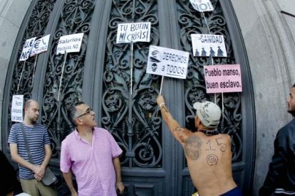 Varios manifestantes cuelgan pancartas en la puerta del Banco de España al inicio de la manifestación más numerosa del 15-O, en Madrid. Foto: EFE