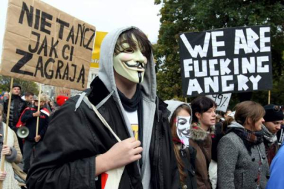 Manifestantes con pancartas y caretas durante la marcha de los indignados en Varsovia, Polonia. Foto: EFE