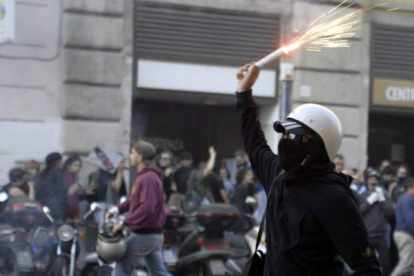 Un encapuchado con una bengala se enfrenta a la policía durante los incidentes que han tenido lugar en la manifestación de los indignados en Roma, Italia. Foto: EFE