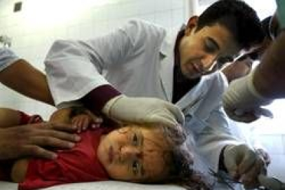 Un médico cura a una niña palestina herida en los bombardeos de Gaza