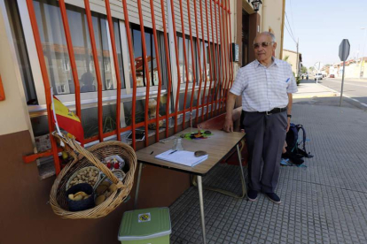 Agapito Trigal posa en el exterior de su casa, en San Miguel del Camino, con los pequeños obsequios que aguar