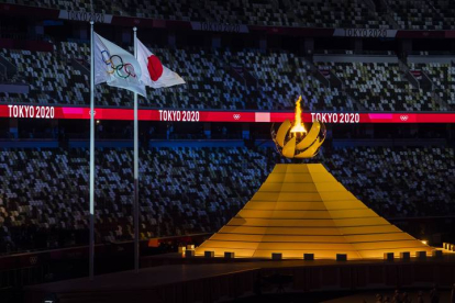Las banderas olímpica y japonesa ondean junto al pebetero encencido, al final de la ceremonia de inauguración de los Juegos de Tokio.  EFE/EPA/LAURENT GILLIERON