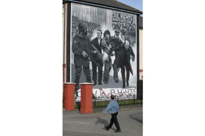 Un hombre camina frente a un mural del «Bloody Sunday».