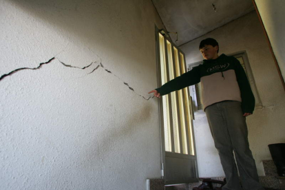 Un joven señala una grieta en su casa, en foto de archivo.