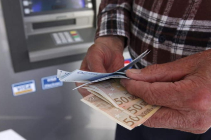 Un hombre muestra dinero tras pasar por un cajero automático. KATIA CHRISTODOU