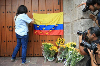 Una ciudadana colombiana coloca una bandera de su país en el portón de la casa del escritor colombiano Gabriel García Márquez, en Ciudad de México, este lunes.