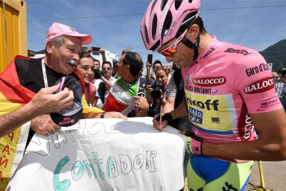 Contador firma autógrafos antes de comenzar la decimoctava etapa.