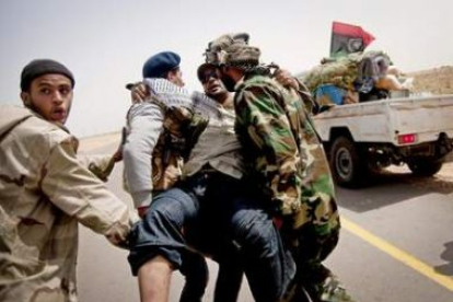 Rebeldes libios trasladan a un compatriota herido en un ataque de las fuerzas de Gadafi.