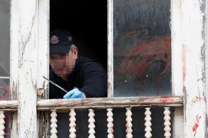 Un ertzaina toma pruebas en la ventana del domicilio.