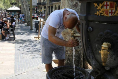 Un turista se refresca en la fuente de Canaletes, en la Rambla de Barcelona. /