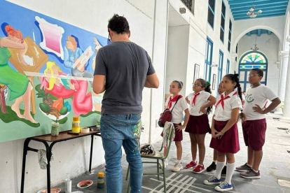 Un grupo de alumnos observa al artista Carlos Álvarez Las Heras mientras pintaba el mural. DL