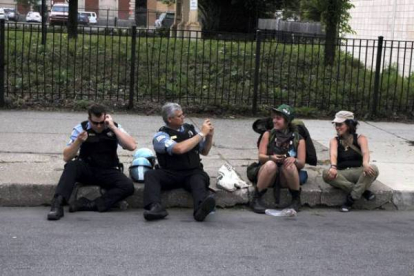 Un policía sentado en la acera junto a otro fotografía a dos manifestantes de la cumbre contra la OTAN. Foto: RICARDO MIR DE FRANCIA / Chicago